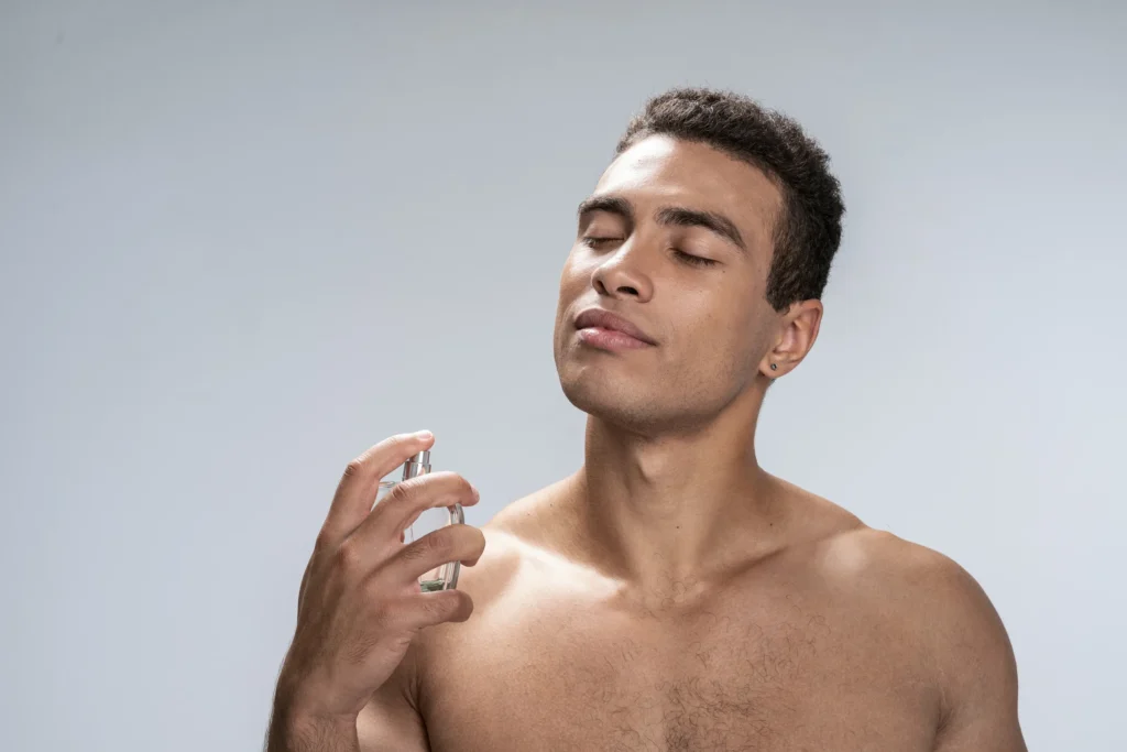 Joven aplicando perfume Valentino hombre en el cuello.