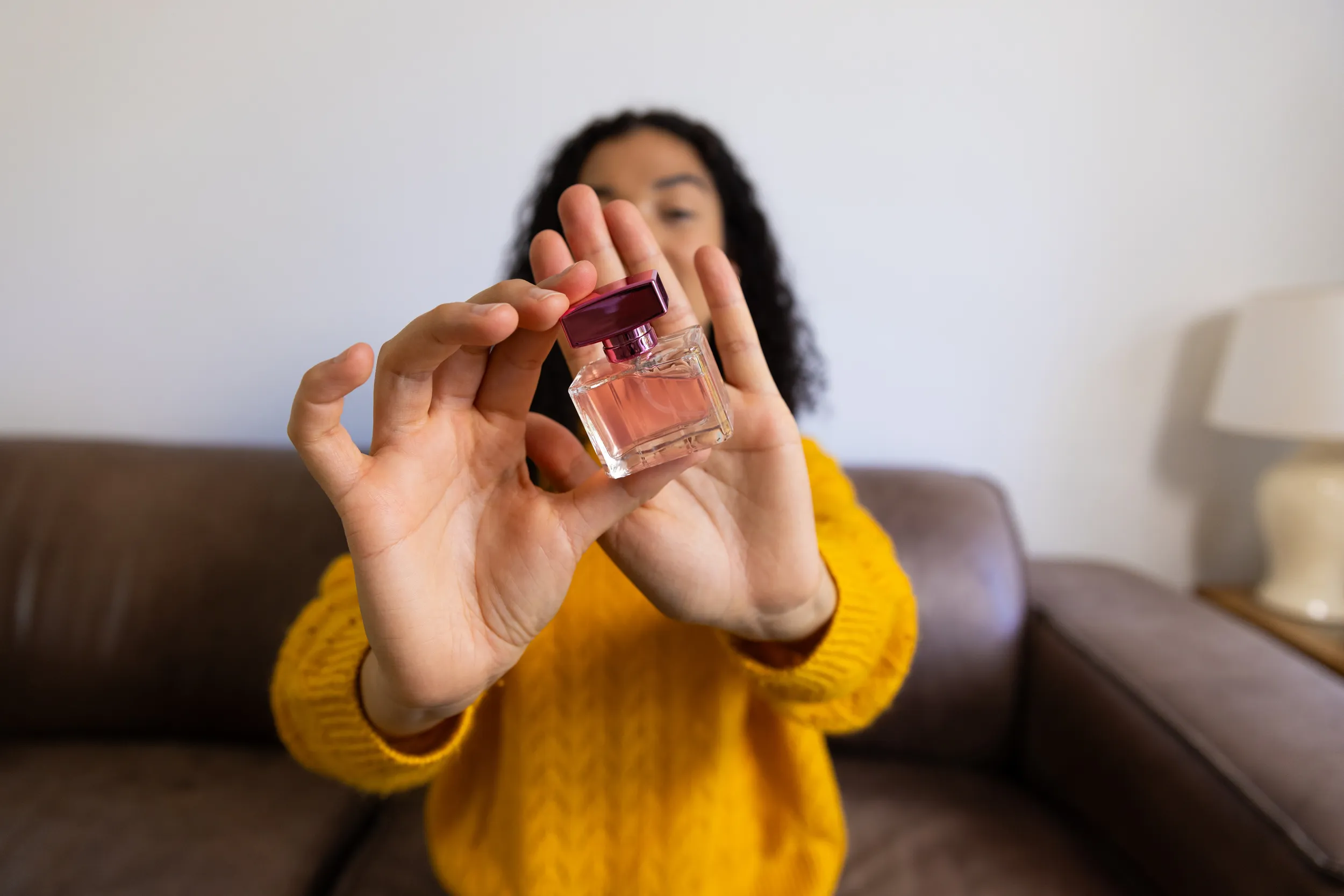 Mujer con suéter amarillo sosteniendo un decant mientras muestra qué es un decant