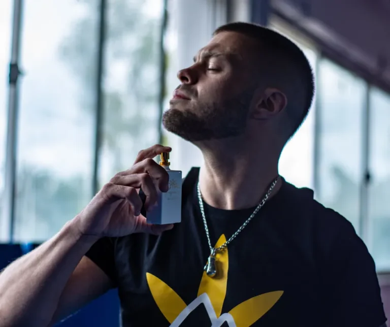 Hombre joven aplicándose perfumes para hombre antes de salir, destacando su estilo y cuidado personal