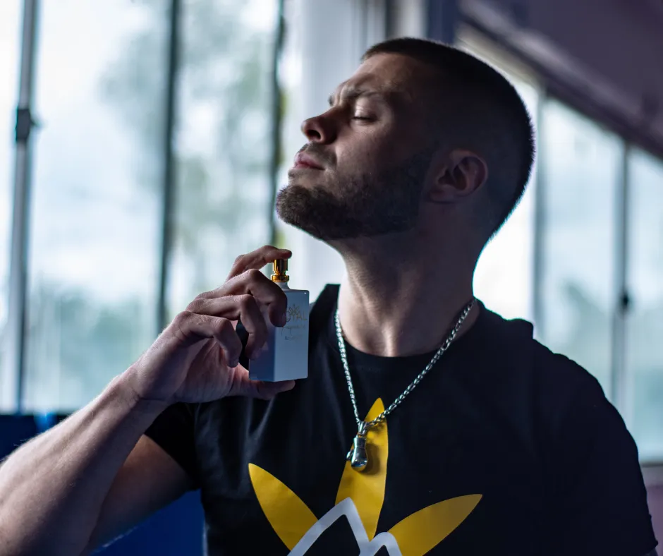Hombre joven aplicándose perfumes para hombre antes de salir, destacando su estilo y cuidado personal