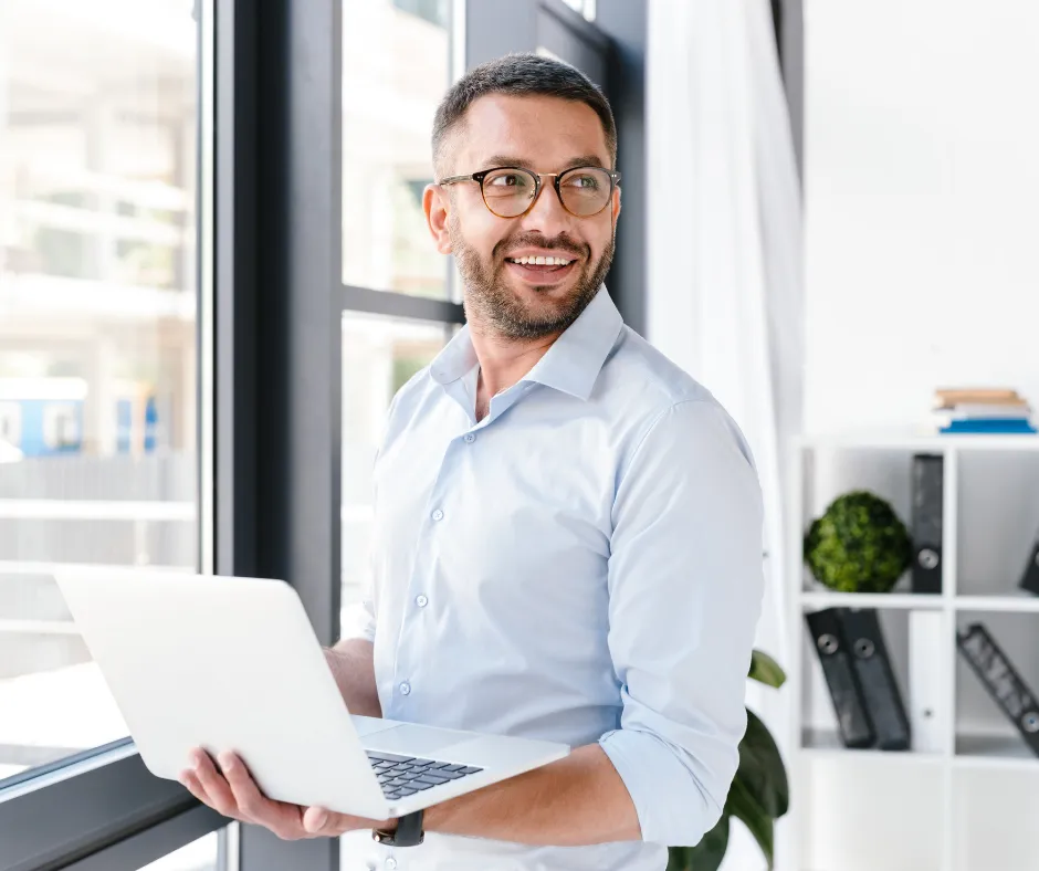 Hombre trabajando en la oficina frente a una computadora blanca, representando perfumes para hombre ideales para el ambiente laboral