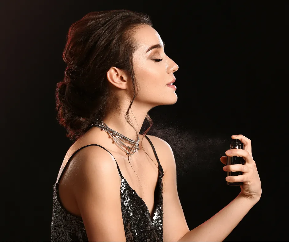 Mujer elegante aplicándose perfumes para mujer en el cuello sobre fondo negro