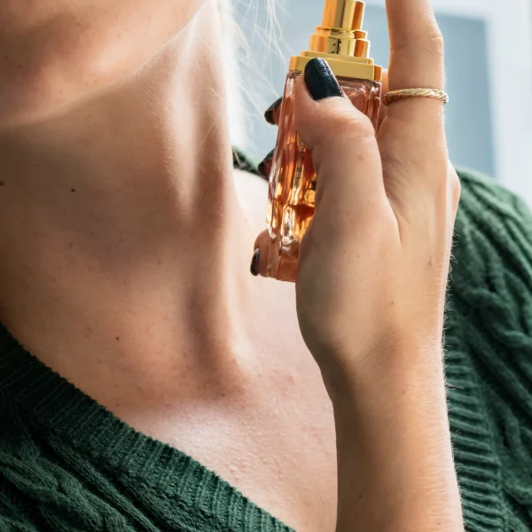 Mujer aplicando perfumes en el cuello para mayor fijación y estela